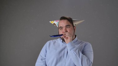 Renkli şapkası ve gürültücüsü olan, neşeli ve neşeli titreşimleri olan bir adam partiden zevk alıyor..