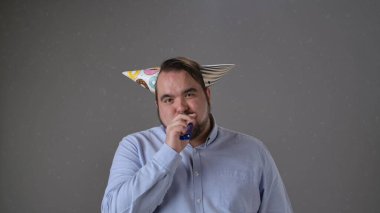 Renkli şapkası ve gürültücüsü olan, neşeli ve neşeli titreşimleri olan bir adam partiden zevk alıyor..