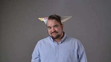 Renkli bir şapkayla partiden zevk alan neşeli ve neşeli bir adam. Parti anlayışı, doğum günü, kutlama.