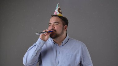 Renkli şapkası ve gürültücüsü olan, neşeli ve neşeli titreşimleri olan bir adam partiden zevk alıyor..