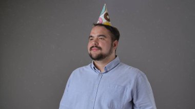 Renkli bir şapkayla partiden zevk alan neşeli ve neşeli bir adam. Parti anlayışı, doğum günü, kutlama.