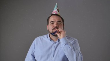 Renkli şapkası ve gürültücüsü olan, neşeli ve neşeli titreşimleri olan bir adam partiden zevk alıyor..