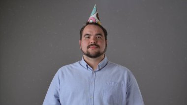 Renkli bir şapkayla partiden zevk alan neşeli ve neşeli bir adam. Parti anlayışı, doğum günü, kutlama.