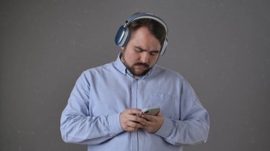 Bir insan rahat, modaya uygun kablosuz kulaklık takarken akıllı telefonuna derinden odaklanır..
