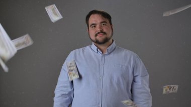 Havada yüzen banknotlarla güvenle duran bir adam refah ve başarı manzarası sergiliyor..