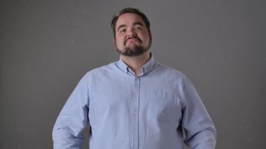 Mavi gömlekli neşeli bir adam başparmağıyla işaret verirken gülümsüyor, pozitifliğini iletiyor. Yavaş çekim