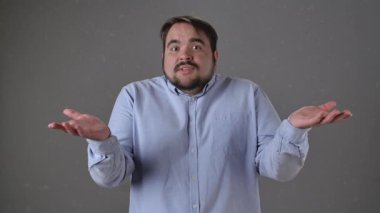 Açık mavi gömlekli bir adam iki eli havada, omuz silkiyor. Yavaş çekim. Kararsız ya da şaşkın görünüyor. Yavaş çekim