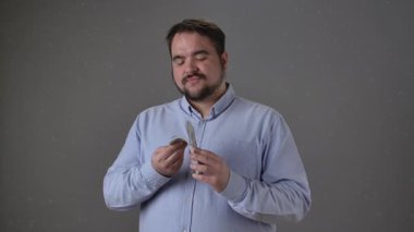 Mavi gömlekli bir adam arka planda odaklanmış bir ifadeyle para sayıyor. Yavaş çekim