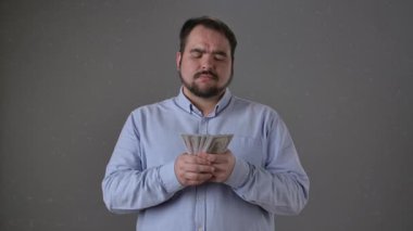 Mavi gömlekli bir adam arka planda odaklanmış bir ifadeyle para sayıyor. Yavaş çekim
