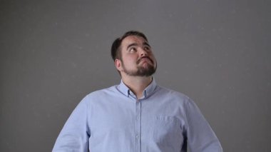 Mavi gömlekli bir adam gülümsüyor ve tek parmakla işaret ediyor, muhtemelen yararlı bir fikir ya da öneriyi işaret ediyor..