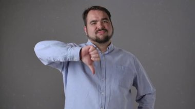 Mavi gömlekli bir adam onaylamadığını ya da tatminsiz olduğunu belirten baş parmağıyla bir jest yapar..