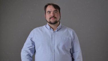 Mavi gömlekli bir adam gülümsüyor ve tek parmakla işaret ediyor, muhtemelen yararlı bir fikir ya da öneriyi işaret ediyor..