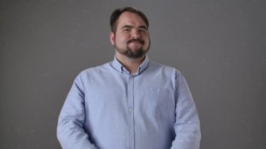 Açık mavi gömlekli bir adam kollarını gri bir arkaplan önünde çapraz yapar, elleri olan bir X sembolü yapar..