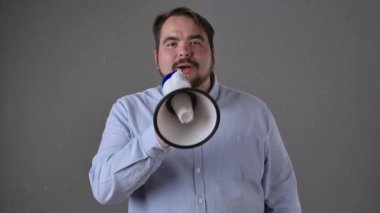 Mavi gömlekli bir adam megafonla konuşuyor, sesli iletişim ve duyuruları vurguluyor..