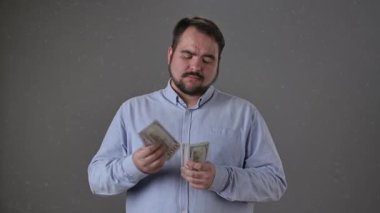 Mavi tişörtlü bir adam arka planda odaklanmış bir ifadeyle parayı tutuyor ve sayıyor..