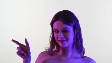 Uzun kahverengi saçlı, yaratıcı ve renkli ışıkların altında sıcak bir gülümsemesi olan genç bir kadın. Neşeli ifadesi mutluluğu ve pozitifliği yansıtıyor..