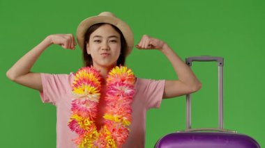 Çiçekli çiçek kollu genç kız mor bavulun yanında duruyor ve kollarını gösteriyor. Krom anahtar yeşil ekran yeşil ekran stüdyo arka plan modelinde izole edilmiş. Yavaş çekim