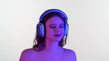 Gözleri kapalı genç bir kadın, duyusal bir deneyime dalmış, büyük kulaklıklarla müzik dinler..