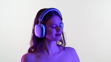 Gözleri kapalı genç bir kadın, duyusal bir deneyime dalmış, büyük kulaklıklarla müzik dinler..