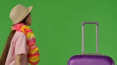 Genç bayan gezgin, mor bavulun yanındaki çerçeveye girer ve mutlu bir şekilde gülümser. Krom anahtar yeşil ekran yeşil ekran stüdyo arka plan modelinde izole edilmiş. Yavaş çekim