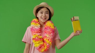 Çiçekli genç kız mor bavulun yanında duruyor ve elinde pasaport ve uçak biletleri var. Krom anahtar yeşil ekran yeşil ekran stüdyo arka plan modelinde izole edilmiş. Yavaş çekim