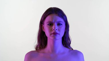 Bir kadın, çarpıcı mavi ve mor ışığın yoğun bir atmosfer yarattığı düz bir zemine dayanır..