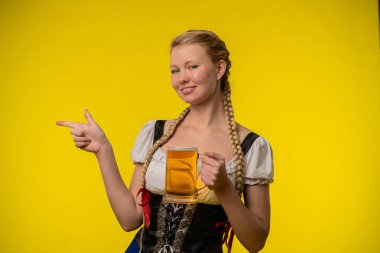 Oktoberfest kostümlü neşeli bir kadın elinde bira kupası tutuyor. Neşeli ifadesi şenliği yansıtıyor..