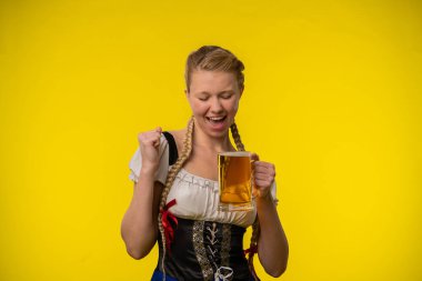 Geleneksel bir kıyafet giymiş bir kadın elinde bira fincanı tutarken gülümsüyor..