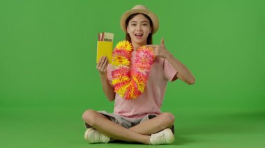 Çiçekli çiçek desenli genç bir kız oturuyor ve pasaportunu uçak biletleriyle ve jestleriyle gösteriyor. Krom anahtar yeşil ekran yeşil ekran stüdyo arka plan modelinde izole edilmiş. Yavaş çekim