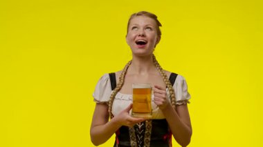 Atkuyruklu ve geleneksel kıyafetli neşeli bir kadın, parlak sarı bir zemin karşısında heyecanlanıyor. Yavaş çekim