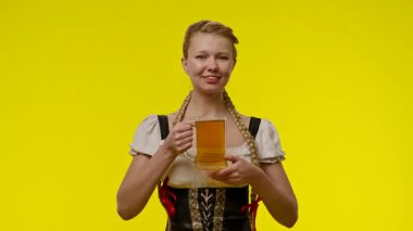 Geleneksel bir kıyafet giymiş bir kadın elinde bira fincanı tutarken gülümsüyor..