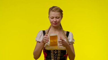 Geleneksel bir kıyafet giymiş bir kadın elinde bira fincanı tutarken gülümsüyor..