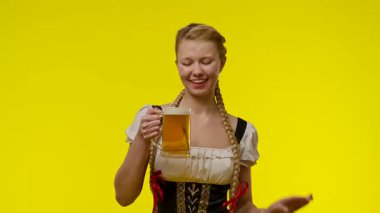Geleneksel bir kıyafet giymiş bir kadın elinde bira fincanı tutarken gülümsüyor..
