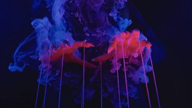 Renkli ve mistik bir dumana bürünmüş ipleri manipüle eden bir çift el. Atmosfer, büyüleyici bir görsel öykü yaratan bir sihir ve gizem ile doludur..