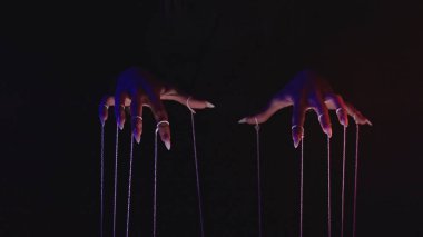 Kukla iplerini kontrol eden uzun tırnaklı, gösterişli, karanlık bir ayar..