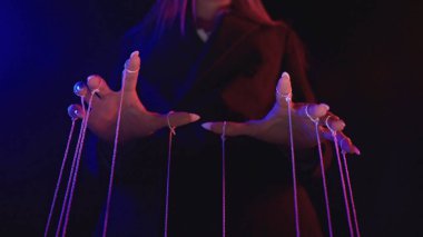 İpleri parmaklarına bağlanmış, loş bir odada ürkütücü, mistik bir atmosfer yaratan biri..