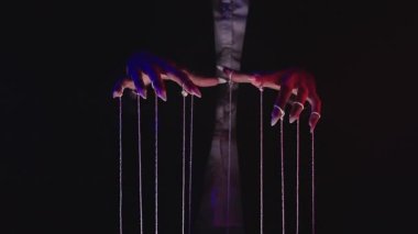 Düşük ışıkta dizgileri manipüle eden eller görüntüsü, kontrol ve manipülasyon temaları. Yavaş çekim