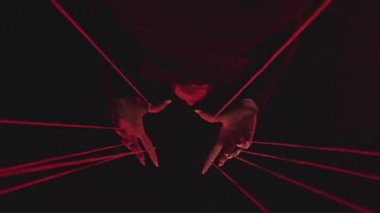 Çarpıcı kırmızı iplik desenleriyle oynanmış, gizemli ve soyutlanmış eller içeren dramatik bir sanatsal fotoğraf. Yavaş çekim