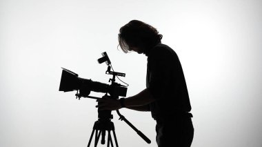 Kamerayı kullanan bir kameramanın silüeti profesyonellik ve hassasiyetle film yapımının özünü yakalıyor..