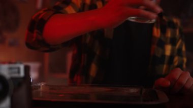 Bir kişi loş ışıklı bir odada, masada akıllı telefon kullanıyor, rahat ve rahat bir ortam öneriyor..