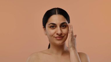 Doğal ve kendine güvenen bir kadın pürüzsüz tenine dokunur, rutin bir cildini ön plana çıkarır..