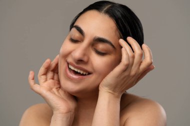 Neşeli bir yüzü olan bir kadının görüntüsü, gözleri kapalı ve elleri yüzüne dokunuyor..