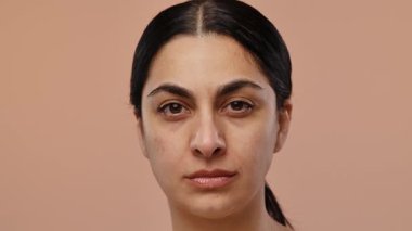 Tarafsız bir zemine dayanan doğal ifadeli bir kadının portresi. Yavaş çekim