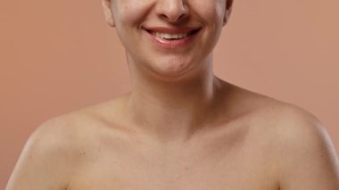 Şeftali arka planında sıcak bir gülümsemesi olan doğal güzelliği ve pozitifliği olan bir insanın fotoğrafı. Yavaş çekim