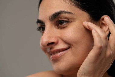 Yumuşak bir şekilde gülümseyen, temiz bir ten ve doğal bir güzellik sergileyen bir kadın. Ilık ışıkta yakalanan.