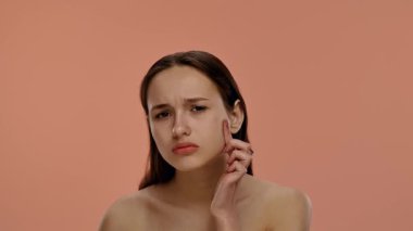 Basit bir arka planda nötr bir ifadeye sahip genç bir kadının portresi. Yavaş çekim