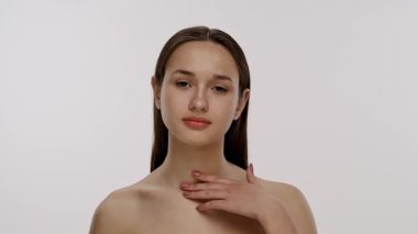 Basit bir arka planda nötr bir ifadeye sahip genç bir kadının yakın plan portresi. Yavaş çekim