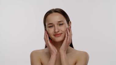 Basit bir arka planda nötr bir ifadeye sahip genç bir kadının yakın plan portresi. Yavaş çekim