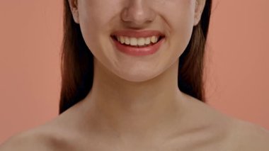 Parlak bir gülüşü olan bir kadının neşeli yakın plan portresi, canlı pembe bir arkaplan üzerine kurulmuş. Yavaş çekim