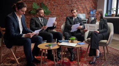 Toplantıda, modern ofis ortamında belge ve çizelgeleri analiz eden bir grup profesyonel. Yavaş çekim.